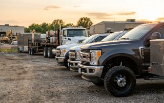 A high-end magazine quality photograph of a commercial fleet parked in a contractor's yard at golden hour, showing clean